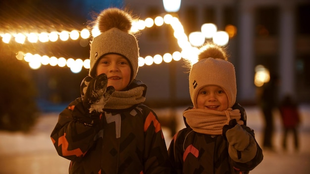 Deux petits enfants debout sur une patinoire publique et regardant dans la caméra