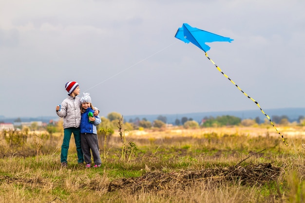 Photo deux petits enfants garçon et fille jouant à l'extérieur avec un cerf-volant