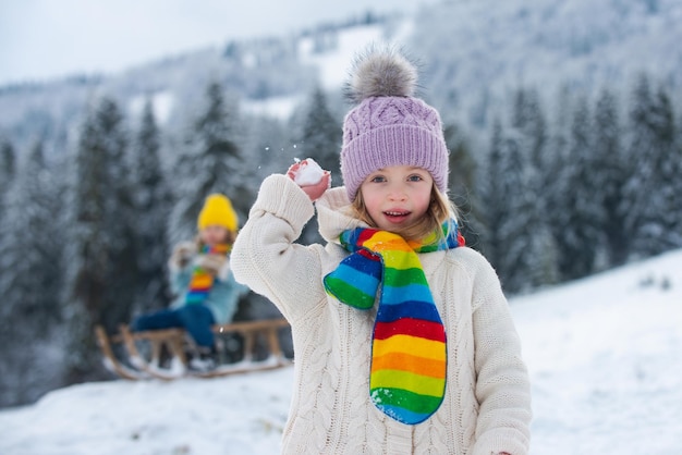 Deux petits enfants s'amusent avec la bataille de boules de neige dans la belle nature d'hiver vêtements tricotés d'hiver f