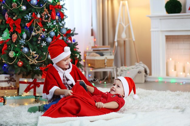 Deux petits frères mignons jouant avec le sac du père Noël sur la surface de décoration de Noël