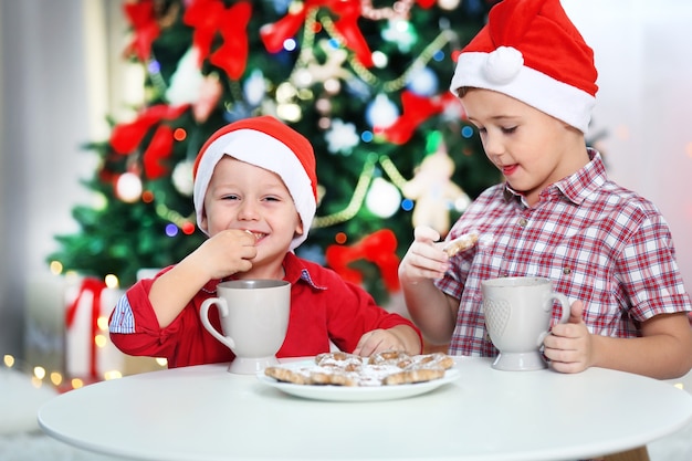 Deux petits frères mignons mangeant des biscuits sur le fond de décoration de Noël