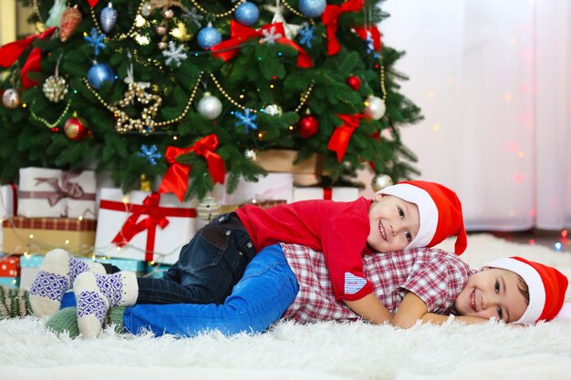 Deux petits frères mignons se trouvent sur un tapis sur la décoration de Noël