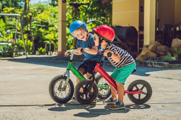 Deux petits garçons enfants s'amusant sur Balance Bike sur une route de campagne tropicale