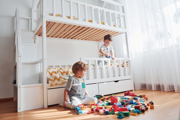 Deux petits garçons s'amusent à l'intérieur dans la chambre avec un jeu de construction en plastique