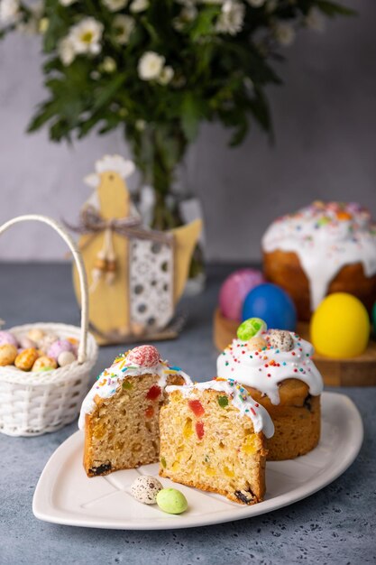 Photo deux petits kulichs de pâques avec des fruits confits en glaçage blanc avec des éclaboussures colorées dans la coupe poulet peint et œufs de caille cuisson traditionnelle de pâque fêtes de pâles focus sélectif en gros plan