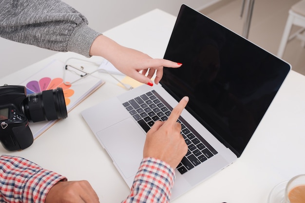 Deux photographes avec appareil photo et ordinateur portable travaillant au bureau