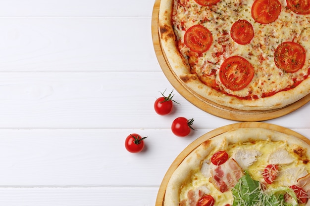 Deux pizzas fraîches sur table en bois blanc