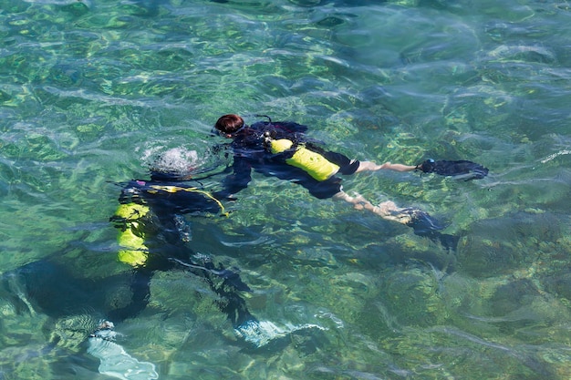 Deux plongeurs nageant sous l'eau au-dessus du récif de corail vif de la mer Rouge en Israël Plongée avec instructeur dans l'eau transparente de la mer bleue Couple Scuba Diver explore et profite du récif de corail