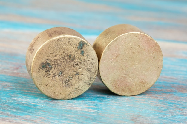 Deux poids en bronze antique pour balances sur fond de bois bleu. Copiez l'espace pour les accessoires de photographie de texte et de nourriture.