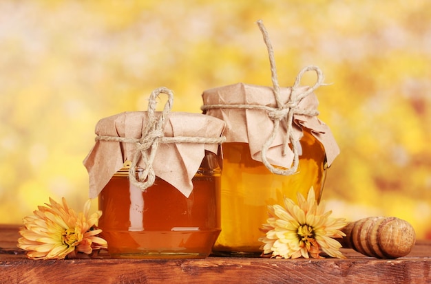 Deux pots de miel et bruine en bois sur table sur fond jaune