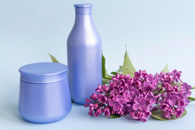 Deux pots violets avec des produits cosmétiques et des crèmes avec des fleurs de lilas fraîches et parfumées