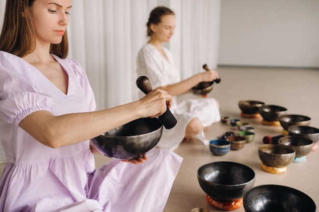 Deux professeurs de yoga jouent sur des bols tibétains dans la salle de sport lors d'une retraite de yoga