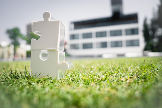 Photo deux puzzles blancs reliés sur l'herbe avec le bâtiment de l'entreprise en arrière-plan