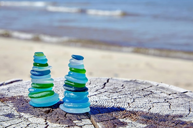 Deux pyramides équilibrées de fragments de bouteilles en verre poli sur une surface en bois altérée contre le fond de la mer