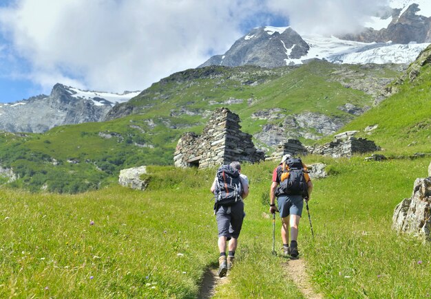 Deux randonneurs avec sac à dos, sentier d'escalade vers le glacier alpin en été