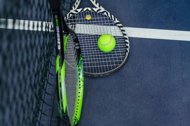 Deux raquettes et balles de tennis appuyées contre le filet Photo horizontale