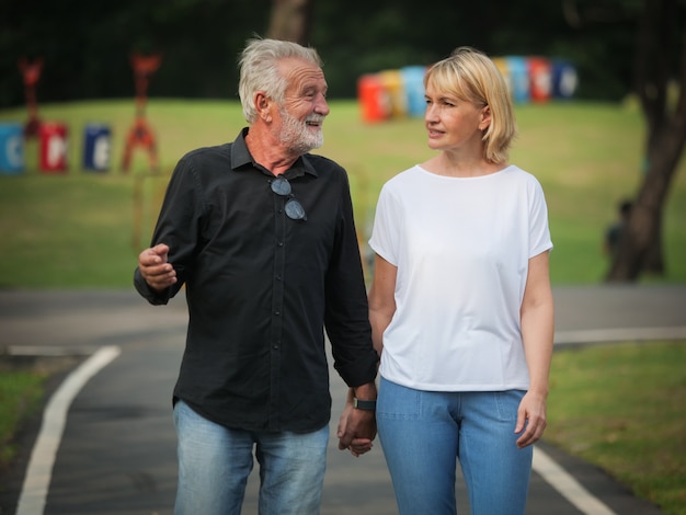 Deux retraités heureux en retraite Un homme et une femme marchent et parlent dans un parc