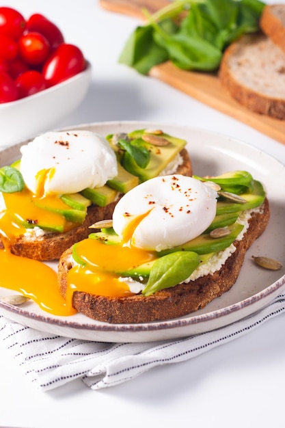 Photo deux sandwichs ouverts à l'avocat avec œuf. concept de céto et de régime. des toasts sains pour le petit-déjeuner.