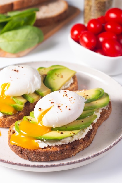 Photo deux sandwichs ouverts à l'avocat avec œuf. concept de céto et de régime. des toasts sains pour le petit-déjeuner.