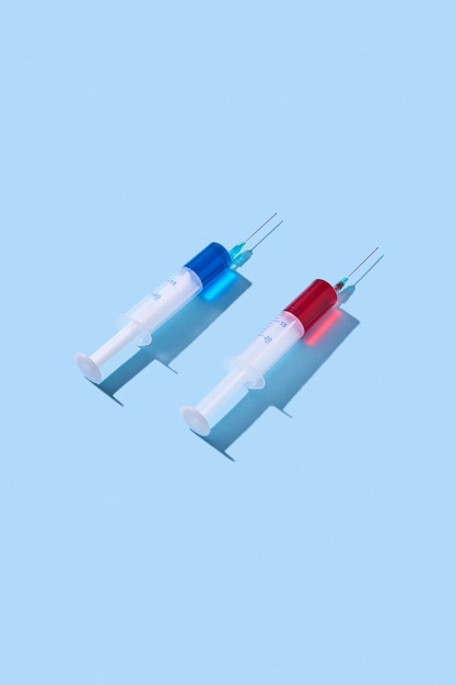 Deux seringues jetables en plastique avec sérum rouge et bleu ou vaccin pour une injection intraveineuse