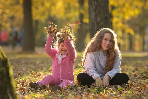 Deux soeurs assises sur le sol dans le parc d'automne