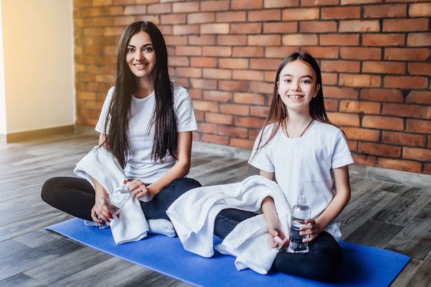 Photo deux soeurs attirantes avec une serviette à l'eau après l'heure du yoga