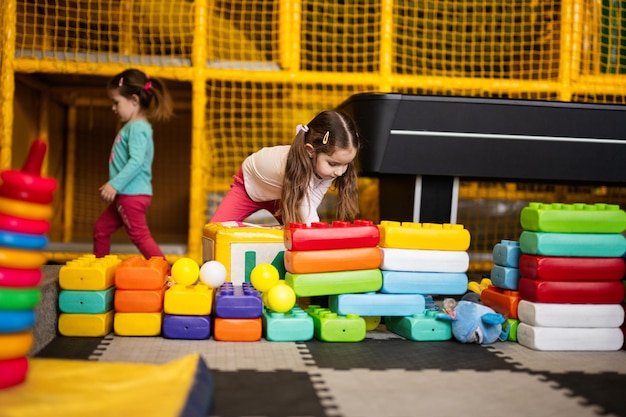 Deux sœurs jouant au centre de jeux pour enfants tout en construisant avec des blocs de plastique colorés