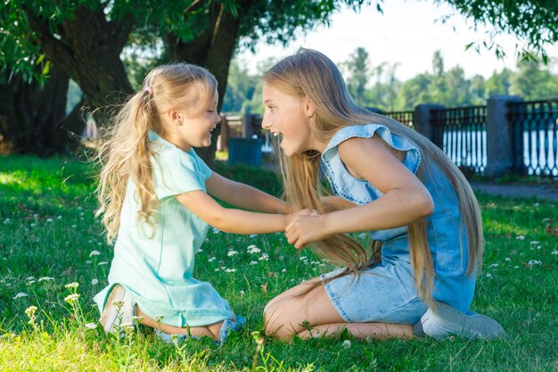 Deux soeurs jouant ensemble dans le parc sur l'herbe