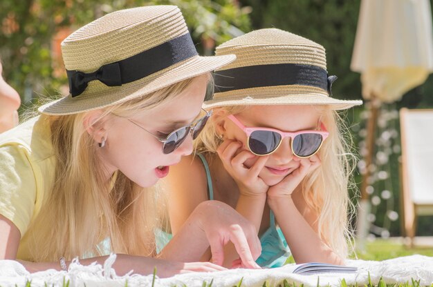 Deux sœurs lisant un livre d'intérêt dans le jardin, plaisir d'été