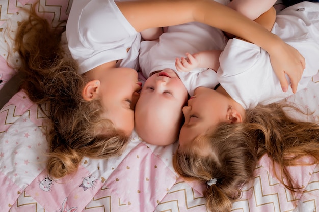 deux sœurs plus âgées tiennent un bébé dans leurs bras