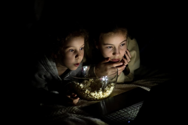 Photo deux soeurs regardent des dessins animés sur l'appareil et s'amusent ensemble loisirs d'enfance