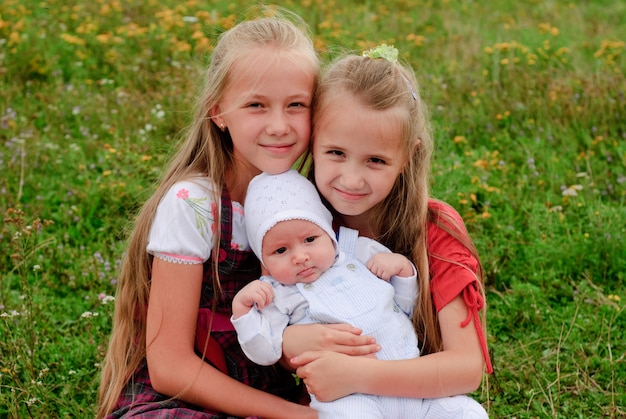 Deux sœurs s'embrassent et petit frère à l'extérieur, famille heureuse