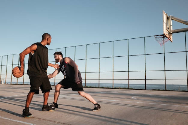 Deux sportifs jouant au basket au terrain de jeu