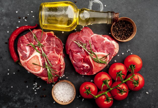 deux steaks de boeuf crus avec des os et des épices sur un fond de pierre