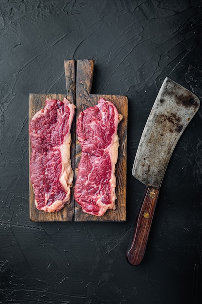 Deux steaks de boeuf frais classiques, sur fond noir, vue de dessus à plat