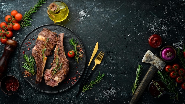 Deux steaks de veau à l'os avec épices thym et romarin Viande barbecue Vue de dessus Vue de dessus à plat sur la table de coupe en pierre noire