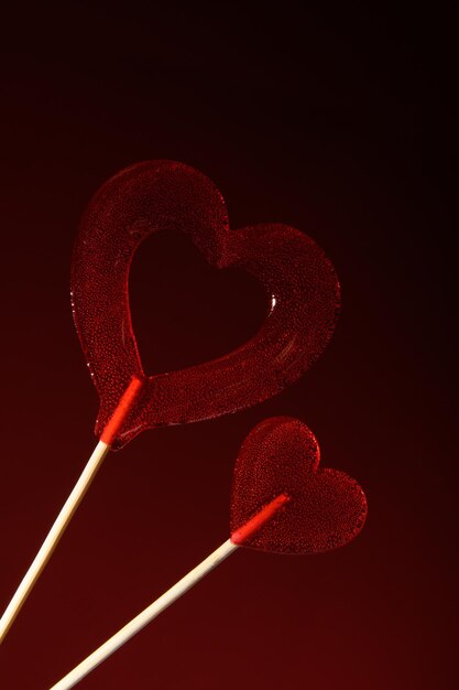 Deux sucettes rouges transparentes en forme de cœur sur un fond rouge foncé Love Banner pour la Saint-Valentin