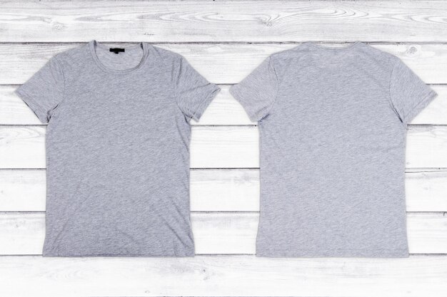 Deux T-shirts vierges gris sur un fond en bois blanc