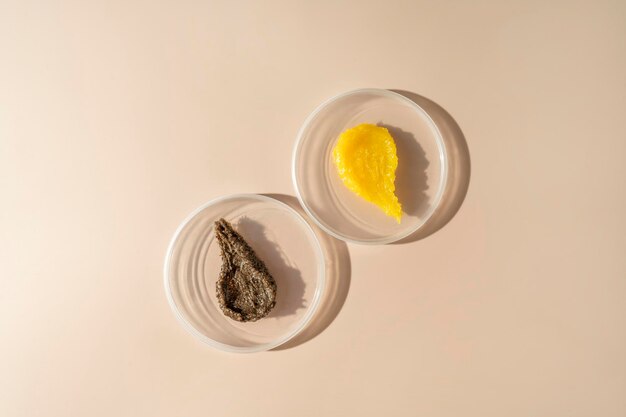 Deux taches cosmétiques de gommage corporel et de crème allongées sur des assiettes sur fond beige
