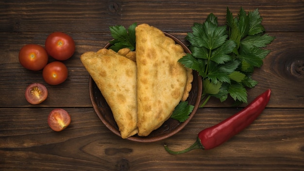 Deux tartes fraîches avec de la viande et des herbes sur une table en bois sombre