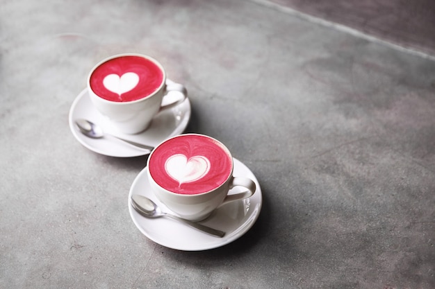 Deux tasses blanches de latte de betterave corolful à la mode avec amour latte d&#39;art.