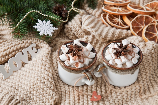 Deux tasses de boisson chaude à la guimauve et un décor de Noël.