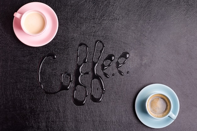 Deux tasses avec une boisson fraîche aromatique du matin sur un cuir écologique artificiel noir décoratif. Vue de dessus.