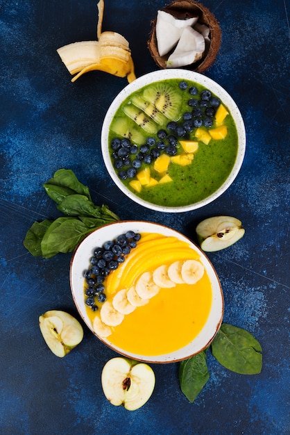 Deux tasses de bol de smoothie différent de fruits verts et jaunes. Le concept d'une alimentation saine. Photo verticale. Vue de dessus.