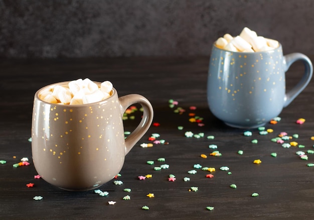 Photo deux tasses de cacao avec des guimauves sur fond sombre avec de petits flocons de neige