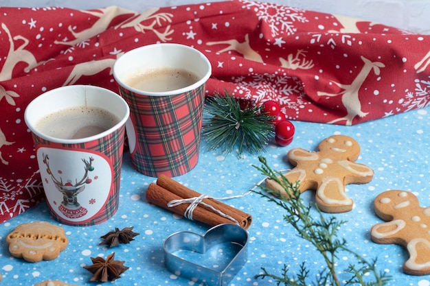 Deux tasses de café avec des bâtons de cannelle et des biscuits sur bleu