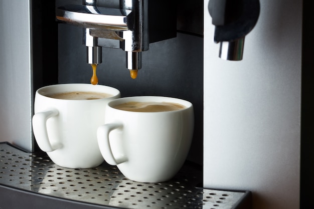 Deux tasses de café blanc dans une machine à café