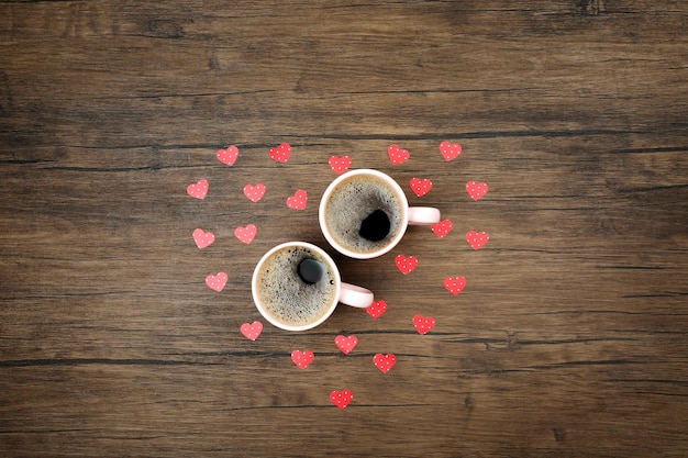 Deux tasses de café avec des coeurs rouges sur la vue de dessus de fond en bois