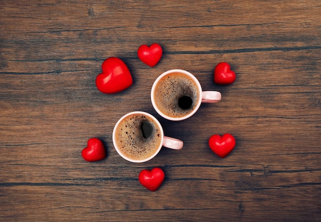 Deux tasses de café avec des coeurs rouges sur la vue de dessus de fond en bois