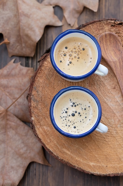 Deux tasses de café avec des feuilles sur fond de bois